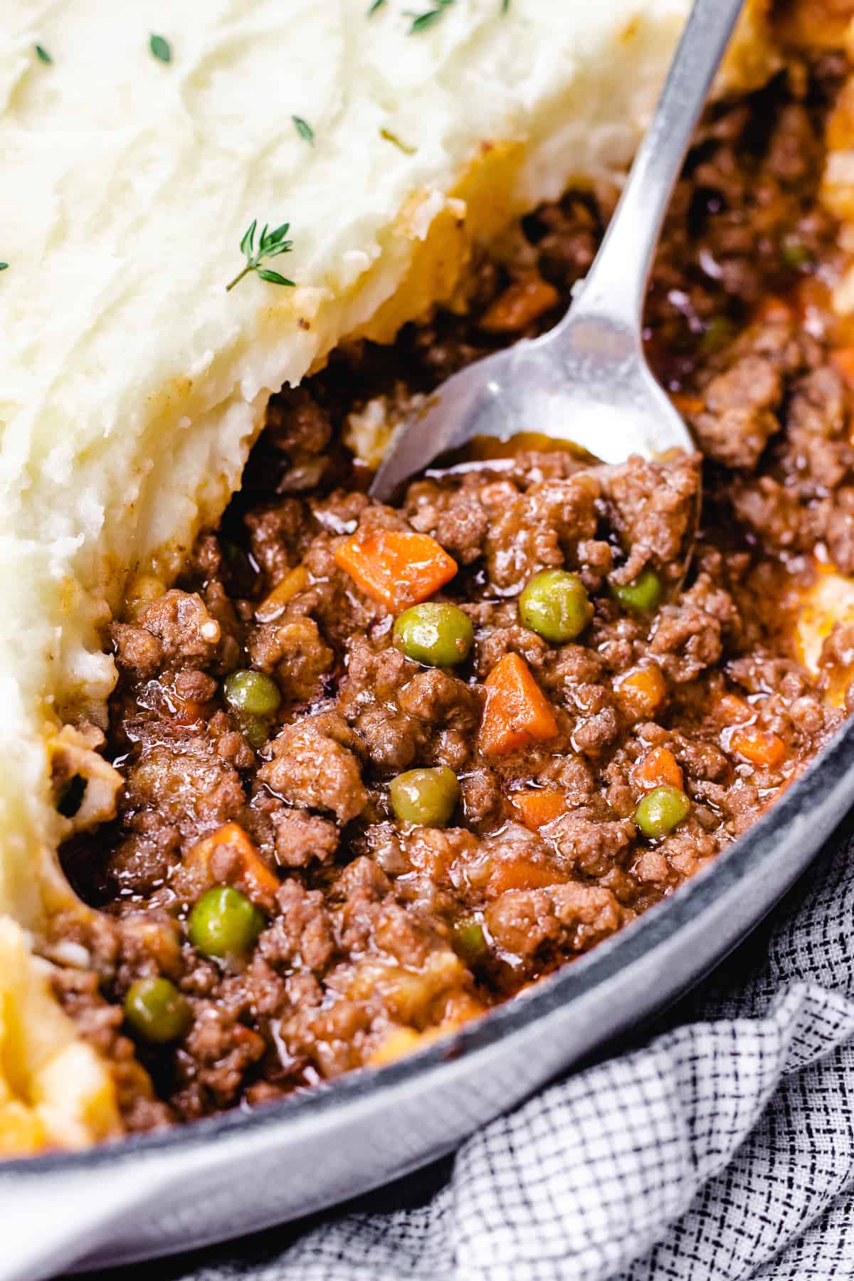 Shepherd's Pie σε μια λευκή κατσαρόλα με ένα κουτάλι να βγαίνει.